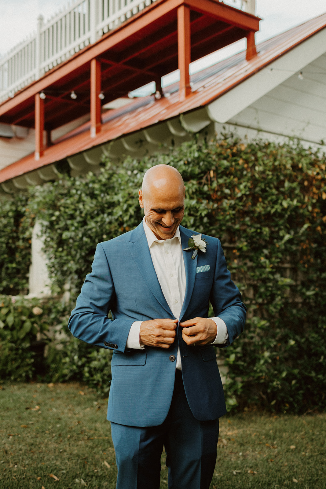 the groom buttoning his navy coat
