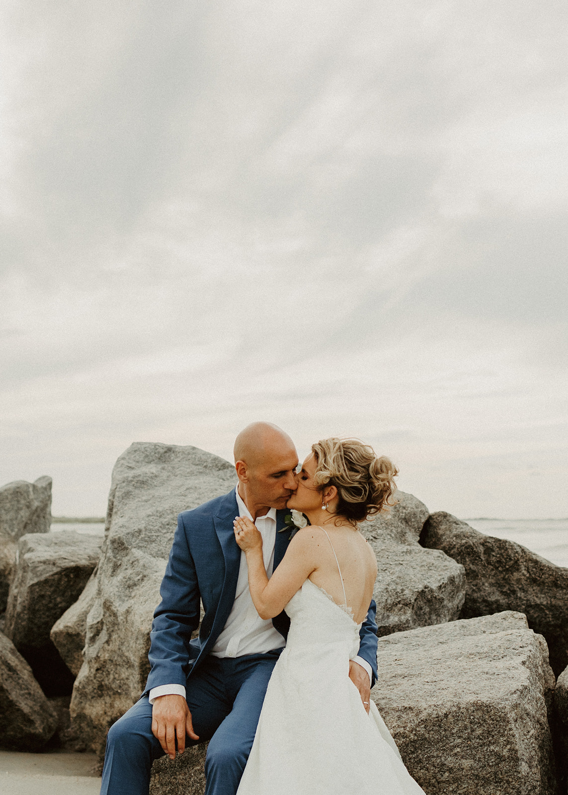 the couple kissing by beach rocks