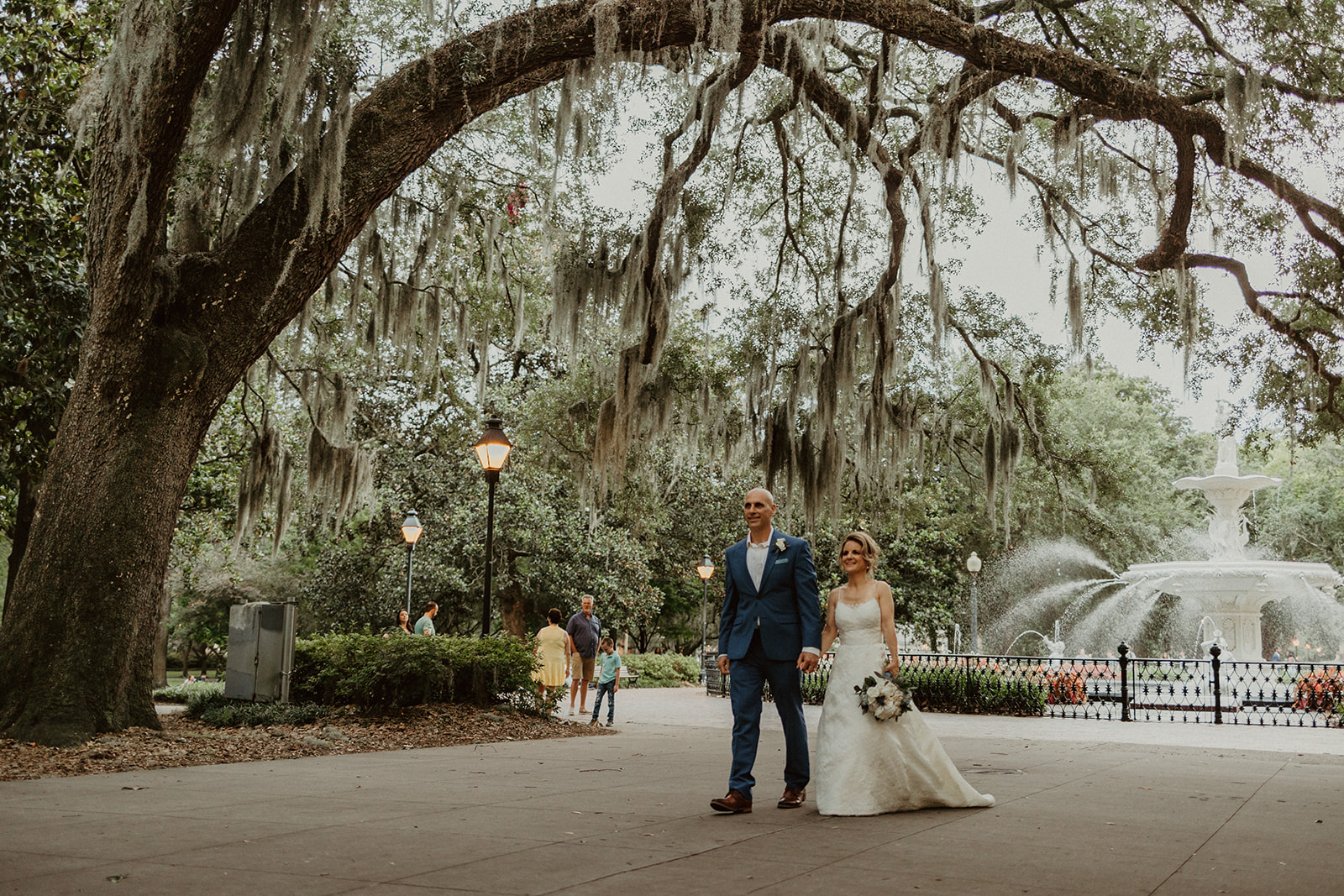 the bride and groom walking under a tree in the park during their Savannah Georgia Elopement