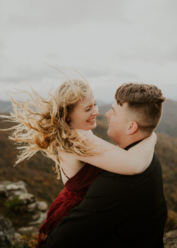the couple smiling at one another as their hair gets blown