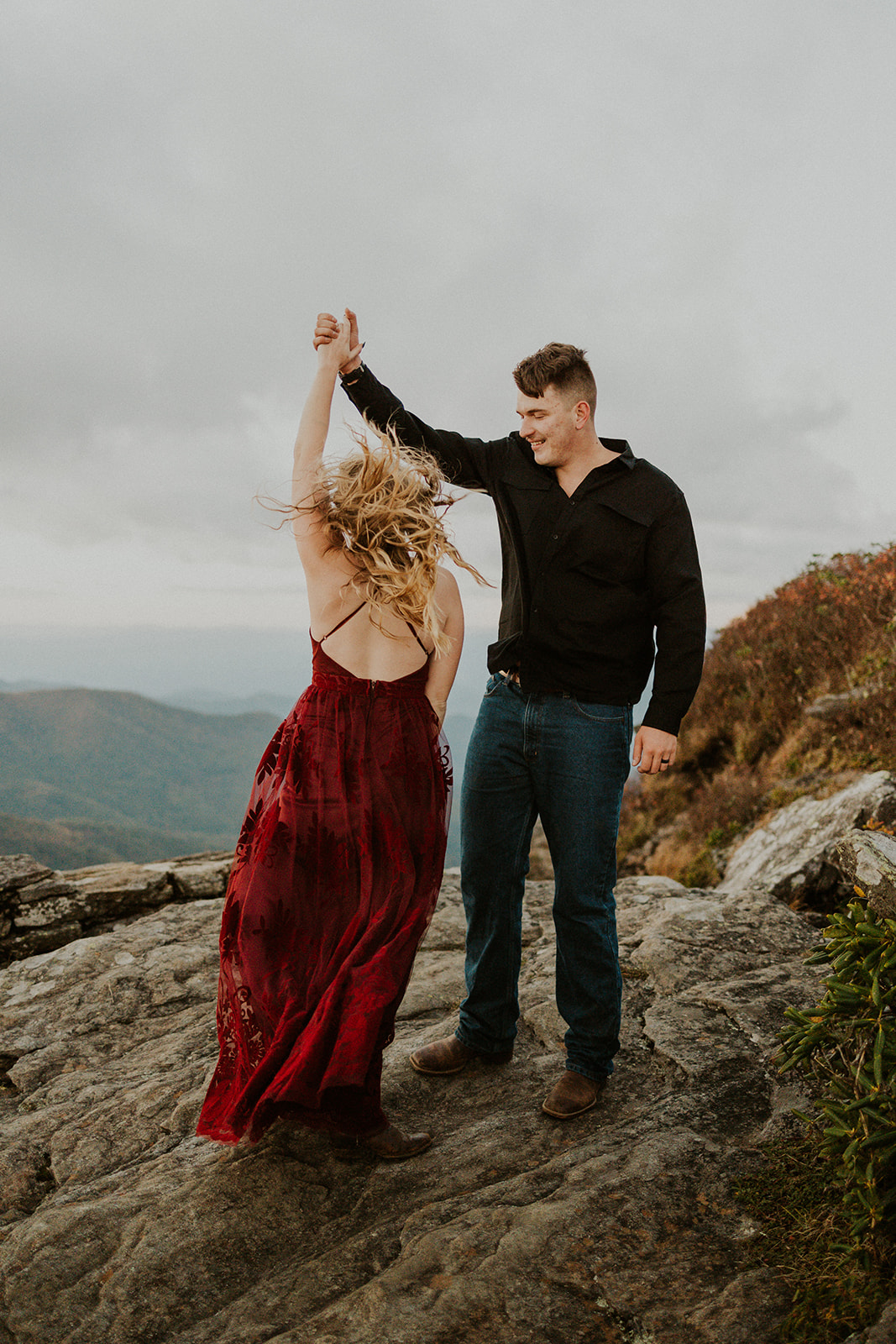the couple dancing in the wind on the top of the mountain
