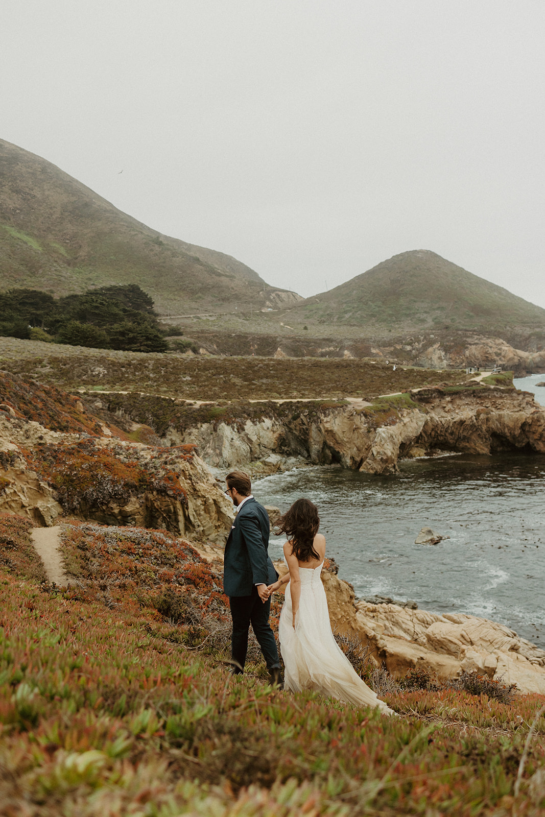 the couple walking along the coast away from their elopement photographer