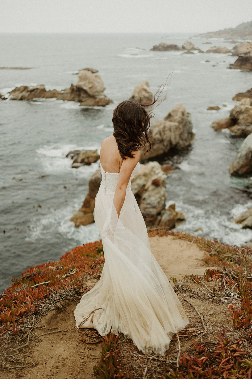 the bride standing with her dress blowing in the wind