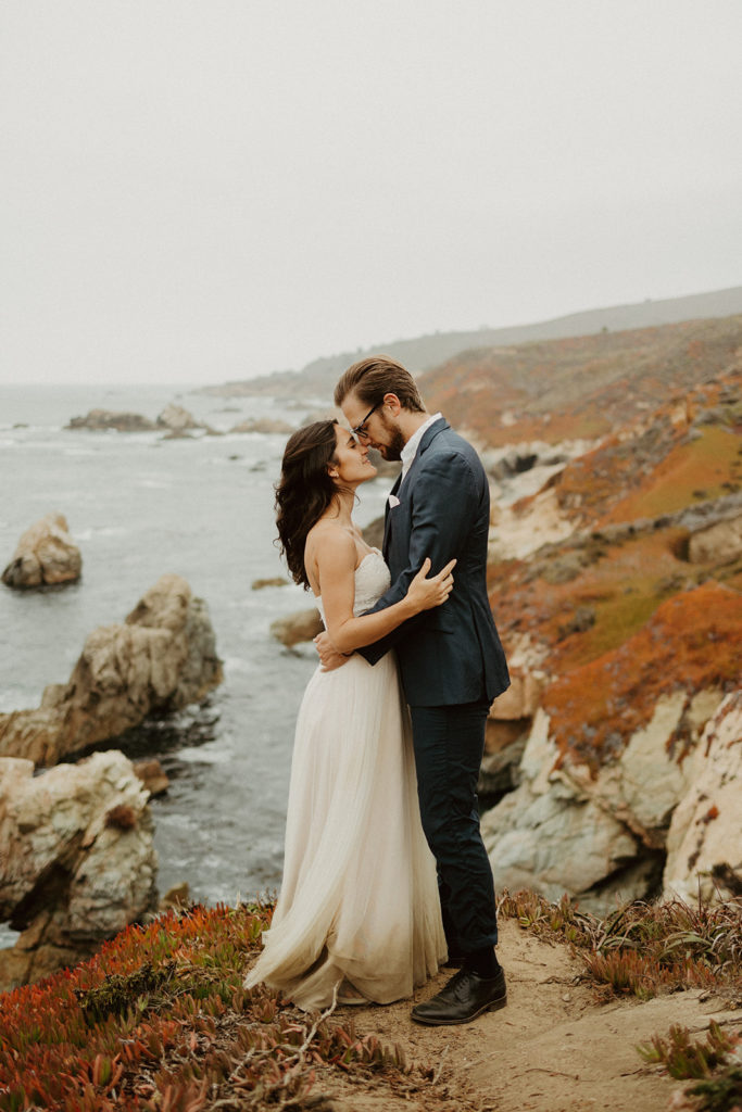 the couple touching foreheads on the cliff at Big Sur
