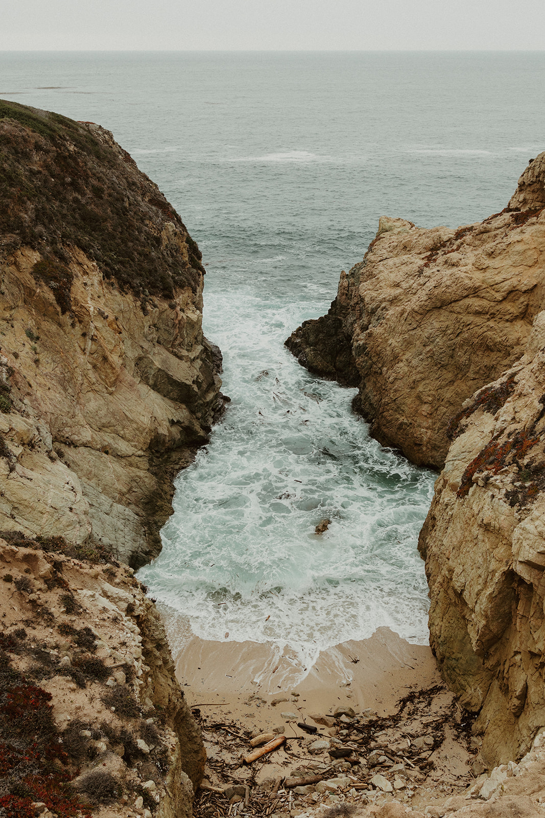 the water running into the coastline at their foggy elopement in big sur