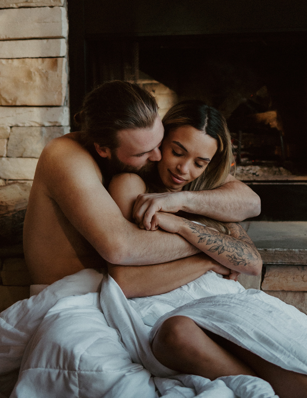 the couple wrapped up in a hug by the fireplace