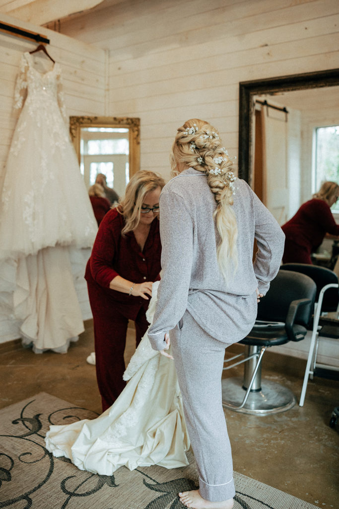 the mother of the bride helping the bride put on her wedding dress