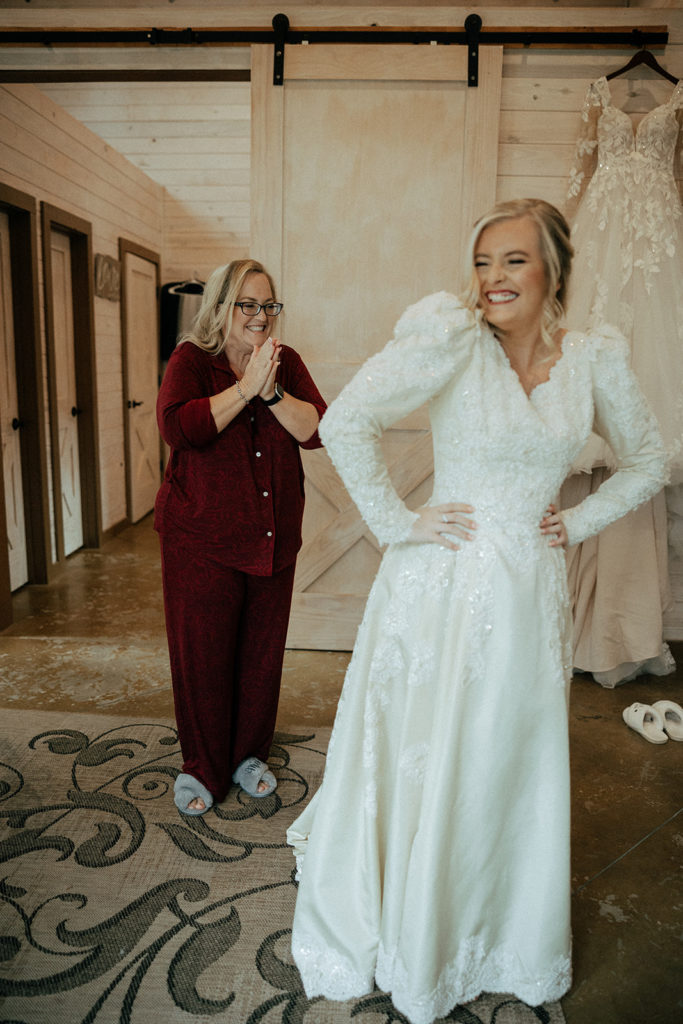 the mother of the bride smiling at the bride's vintage wedding dress